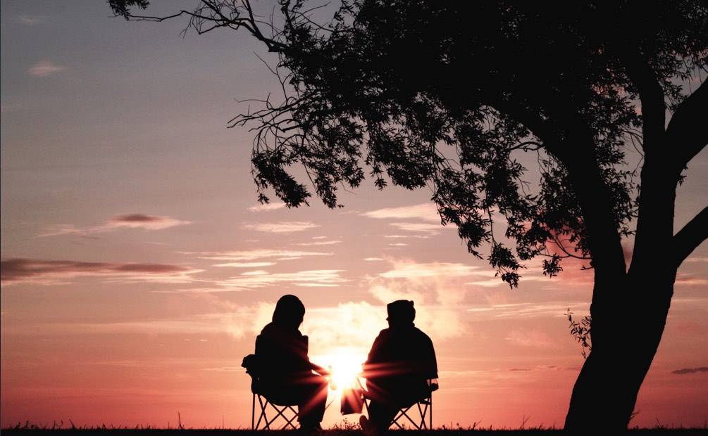 two people watching the setting sun sitting on chairs